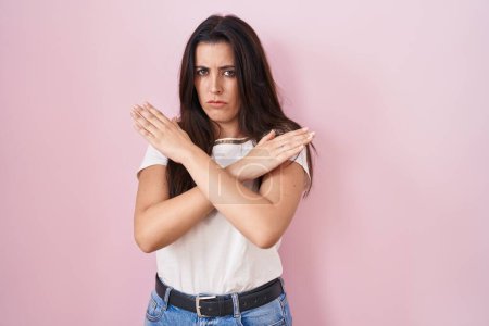 Téléchargez les photos : Jeune femme brune debout sur fond rose expression de rejet croisant les bras faisant signe négatif, visage en colère - en image libre de droit