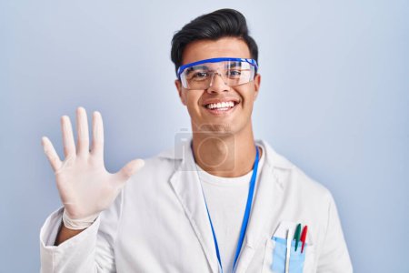 Photo for Hispanic man working as scientist showing and pointing up with fingers number five while smiling confident and happy. - Royalty Free Image