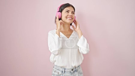 Téléchargez les photos : Jeune belle femme hispanique écoutant de la musique et dansant sur fond rose isolé - en image libre de droit