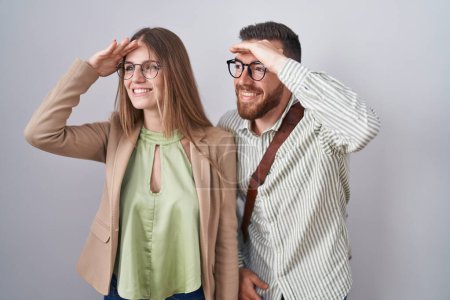 Téléchargez les photos : Jeune couple debout sur fond blanc très heureux et souriant regardant loin avec la main sur la tête. concept de recherche. - en image libre de droit