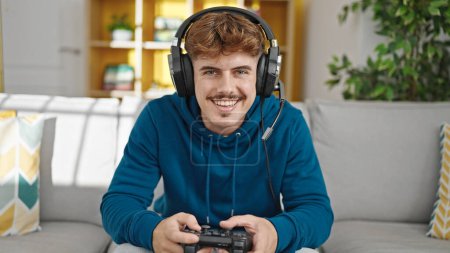 Photo for Young hispanic man playing video game sitting on sofa smiling at home - Royalty Free Image
