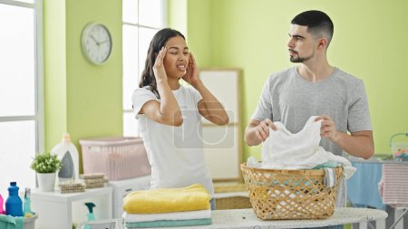 Photo for Exhausted love-struck couple suffering headache while tackling tedious laundry chores in their beautiful indoor laundry room - Royalty Free Image