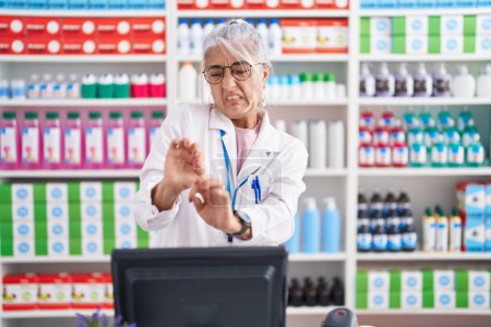 Photo for Middle age woman with tattoos working at pharmacy drugstore disgusted expression, displeased and fearful doing disgust face because aversion reaction. - Royalty Free Image