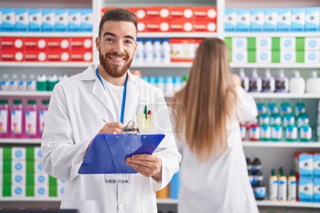 Photo for Man and woman pharmacists smiling confident writing on document at pharmacy - Royalty Free Image