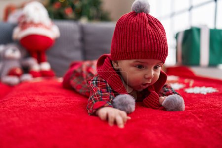 Téléchargez les photos : Adorable bébé caucasien couché sur le canapé par arbre de Noël à la maison - en image libre de droit