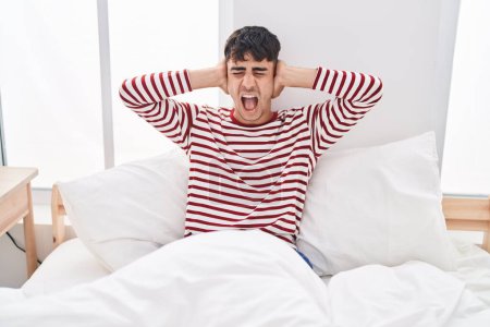 Photo for Young hispanic man covering ears for noise at bedroom - Royalty Free Image