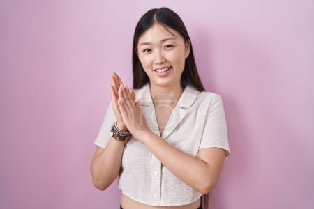 Photo for Chinese young woman standing over pink background clapping and applauding happy and joyful, smiling proud hands together - Royalty Free Image