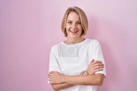 Téléchargez les photos : Jeune femme caucasienne debout sur fond rose heureux visage souriant avec les bras croisés regardant la caméra. personne positive. - en image libre de droit