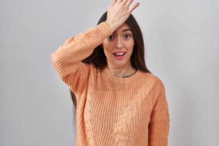 Photo for Young brunette woman standing over white background surprised with hand on head for mistake, remember error. forgot, bad memory concept. - Royalty Free Image