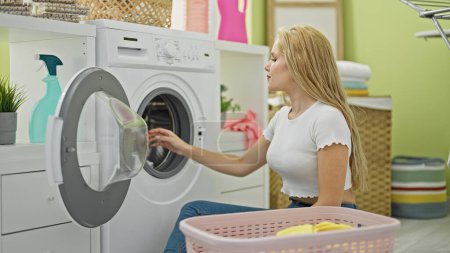 Téléchargez les photos : Jeune femme blonde laver les vêtements à la buanderie - en image libre de droit