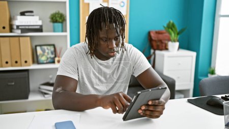 Téléchargez les photos : Africain américain homme d'affaires en utilisant touchpad au bureau - en image libre de droit