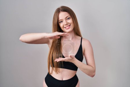 Photo for Young caucasian woman wearing lingerie gesturing with hands showing big and large size sign, measure symbol. smiling looking at the camera. measuring concept. - Royalty Free Image