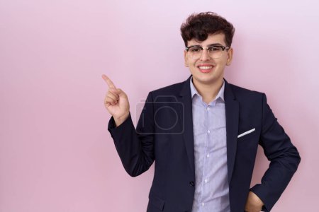 Photo for Young non binary man with beard wearing suit and tie with a big smile on face, pointing with hand and finger to the side looking at the camera. - Royalty Free Image