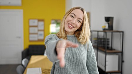 Foto de Joven mujer rubia trabajadora de negocios sonriendo confiada apretón de manos en la oficina - Imagen libre de derechos