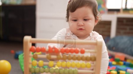 Photo for Adorable toddler playing with abacus sitting on floor at kindergarten - Royalty Free Image