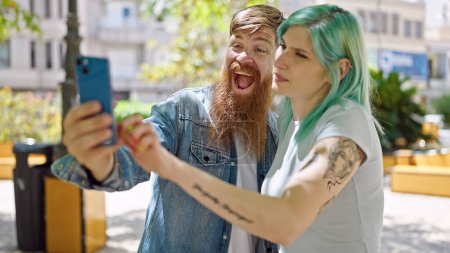 Téléchargez les photos : Homme et femme couple souriant confiant faire selfie par smartphone au parc - en image libre de droit