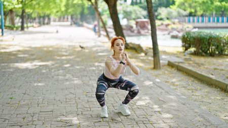 Téléchargez les photos : Jeune rousse femme portant des vêtements de sport entraînement jambes exercice au parc - en image libre de droit
