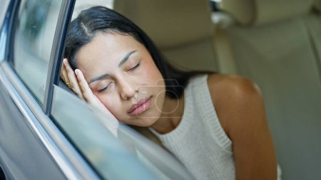 Photo for Young beautiful hispanic woman passenger sitting on car sleeping at street - Royalty Free Image