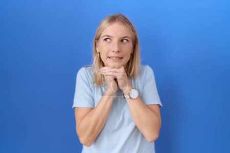 Photo for Young caucasian woman wearing casual blue t shirt laughing nervous and excited with hands on chin looking to the side - Royalty Free Image