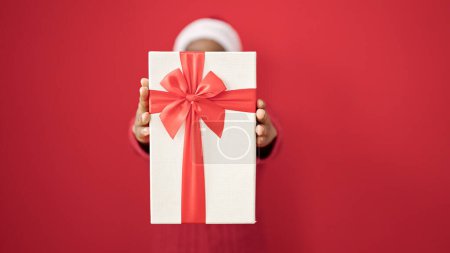 Photo for African american woman holding christmas gift over isolated red background - Royalty Free Image