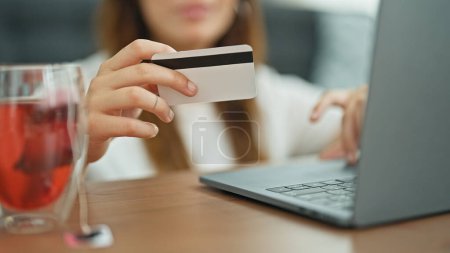 Foto de Joven hermosa mujer hispana de compras con portátil y tarjeta de crédito sentado en el suelo en casa - Imagen libre de derechos