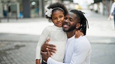 Foto de Padre e hija afroamericanos sonriendo confiados abrazándose en la calle - Imagen libre de derechos