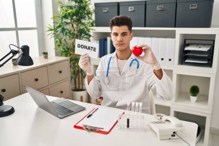 Photo for Young hispanic doctor man supporting organs donations relaxed with serious expression on face. simple and natural looking at the camera. - Royalty Free Image