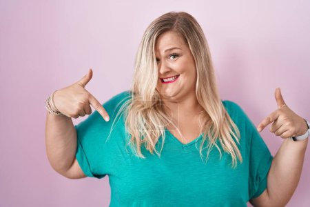 Photo for Caucasian plus size woman standing over pink background looking confident with smile on face, pointing oneself with fingers proud and happy. - Royalty Free Image