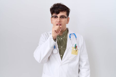 Téléchargez les photos : Jeune homme non binaire portant l'uniforme de médecin et stéthoscope se sentant mal et la toux comme symptôme du rhume ou de la bronchite. concept de soins de santé. - en image libre de droit