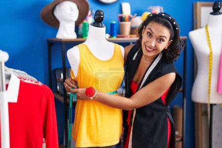 Téléchargez les photos : Jeune belle femme hispanique tailleur souriant confiant t-shirt de mesure à l'usine de vêtements - en image libre de droit
