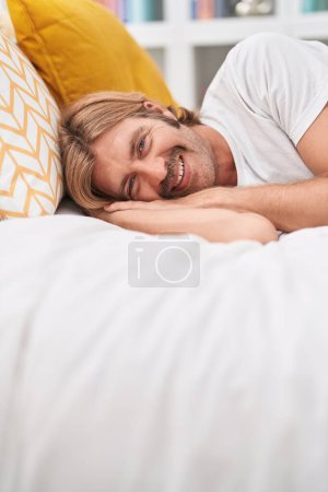 Téléchargez les photos : Young blond man smiling confident lying on bed at bedroom - en image libre de droit