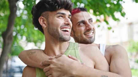 Téléchargez les photos : Deux hommes couple souriant confiant se serrant dans ses bras au parc - en image libre de droit