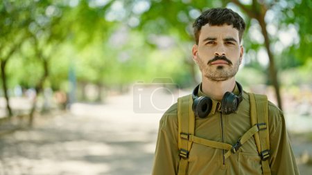 Foto de Joven turista hispano con mochila y auriculares en el parque - Imagen libre de derechos