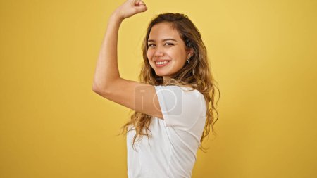 Téléchargez les photos : Jeune belle femme hispanique souriant confiant faire un geste fort avec le bras sur fond jaune isolé - en image libre de droit
