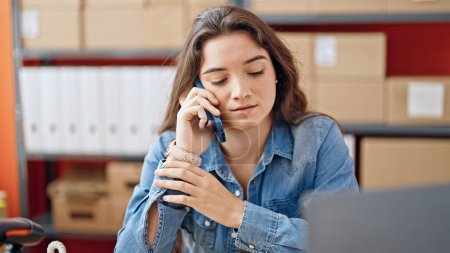 Foto de Mujer hispana hermosa joven comercio electrónico trabajador de negocios hablando en el teléfono inteligente que trabaja en la oficina - Imagen libre de derechos