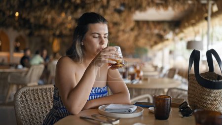 Téléchargez les photos : Jeune femme hispanique buvant un verre de vermouth au restaurant - en image libre de droit