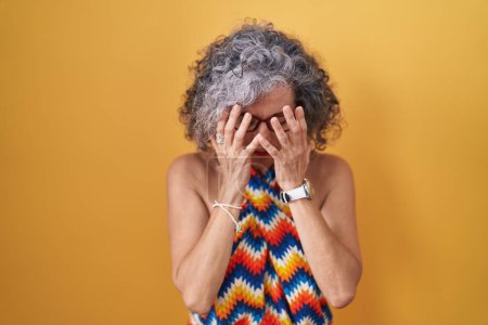 Photo for Middle age woman with grey hair standing over yellow background with sad expression covering face with hands while crying. depression concept. - Royalty Free Image
