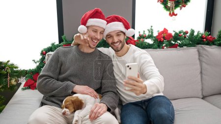 Foto de Dos hombres pareja celebrando la Navidad hacen selfie por teléfono inteligente en casa - Imagen libre de derechos