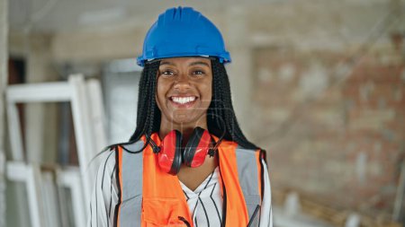 Téléchargez les photos : African American femme constructeur souriant confiance debout sur le chantier de construction - en image libre de droit