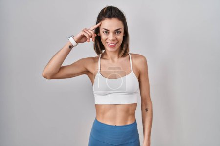 Photo for Hispanic woman wearing sportswear over isolated background smiling pointing to head with one finger, great idea or thought, good memory - Royalty Free Image