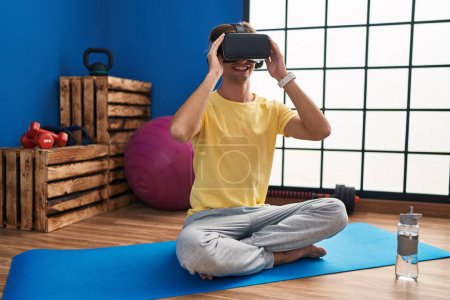 Photo for Young caucasian man sitting on floor using virtual reality glasses at sport center - Royalty Free Image