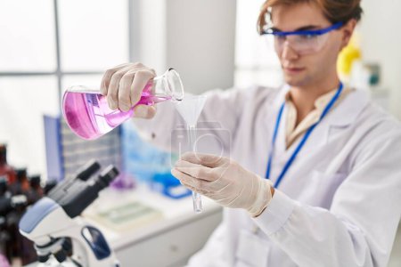 Foto de Hombre joven caucásico científico vertiendo líquido en tubo de ensayo en laboratorio - Imagen libre de derechos