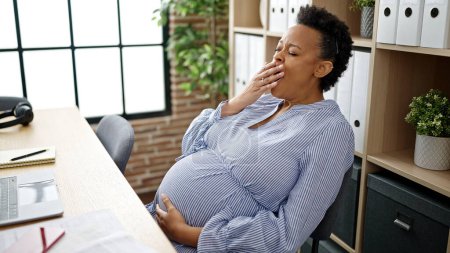 Photo for Young pregnant woman business worker tired sitting on table yawning at office - Royalty Free Image