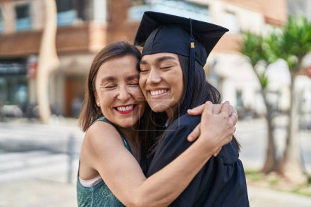 Photo for Two women mother and graduated daughter hugging each other at street - Royalty Free Image