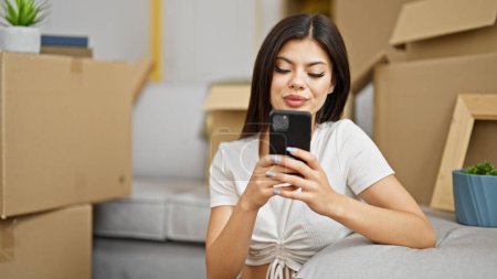 Photo for Young caucasian woman using smartphone sitting on floor at new home - Royalty Free Image