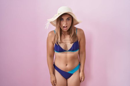 Photo for Young hispanic woman wearing bikini over pink background afraid and shocked with surprise and amazed expression, fear and excited face. - Royalty Free Image