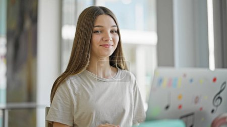 Téléchargez les photos : Jeune belle étudiante utilisant un ordinateur portable étudiant à la bibliothèque - en image libre de droit