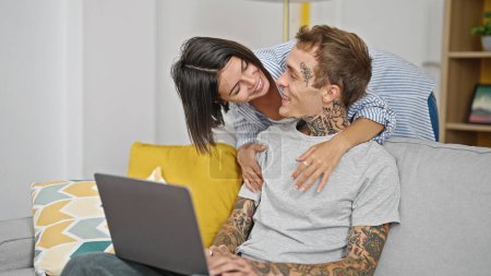 Téléchargez les photos : Beau couple s'embrassant à l'aide d'un ordinateur portable à la maison - en image libre de droit