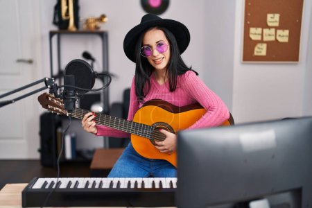Téléchargez les photos : Young caucasian woman musician smiling confident playing classical guitar at music studio - en image libre de droit