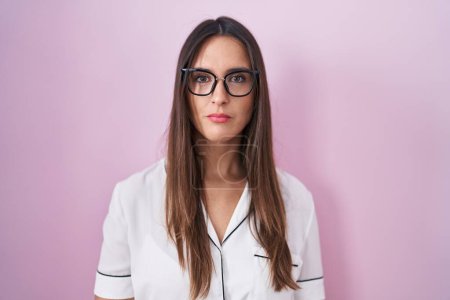 Photo for Young brunette woman wearing glasses standing over pink background relaxed with serious expression on face. simple and natural looking at the camera. - Royalty Free Image